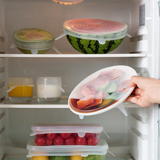 Hand opening a refrigerator door with a container of food inside.