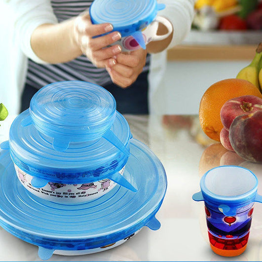 Blue silicone lid on a kitchen counter with colorful cups and fruits in the background